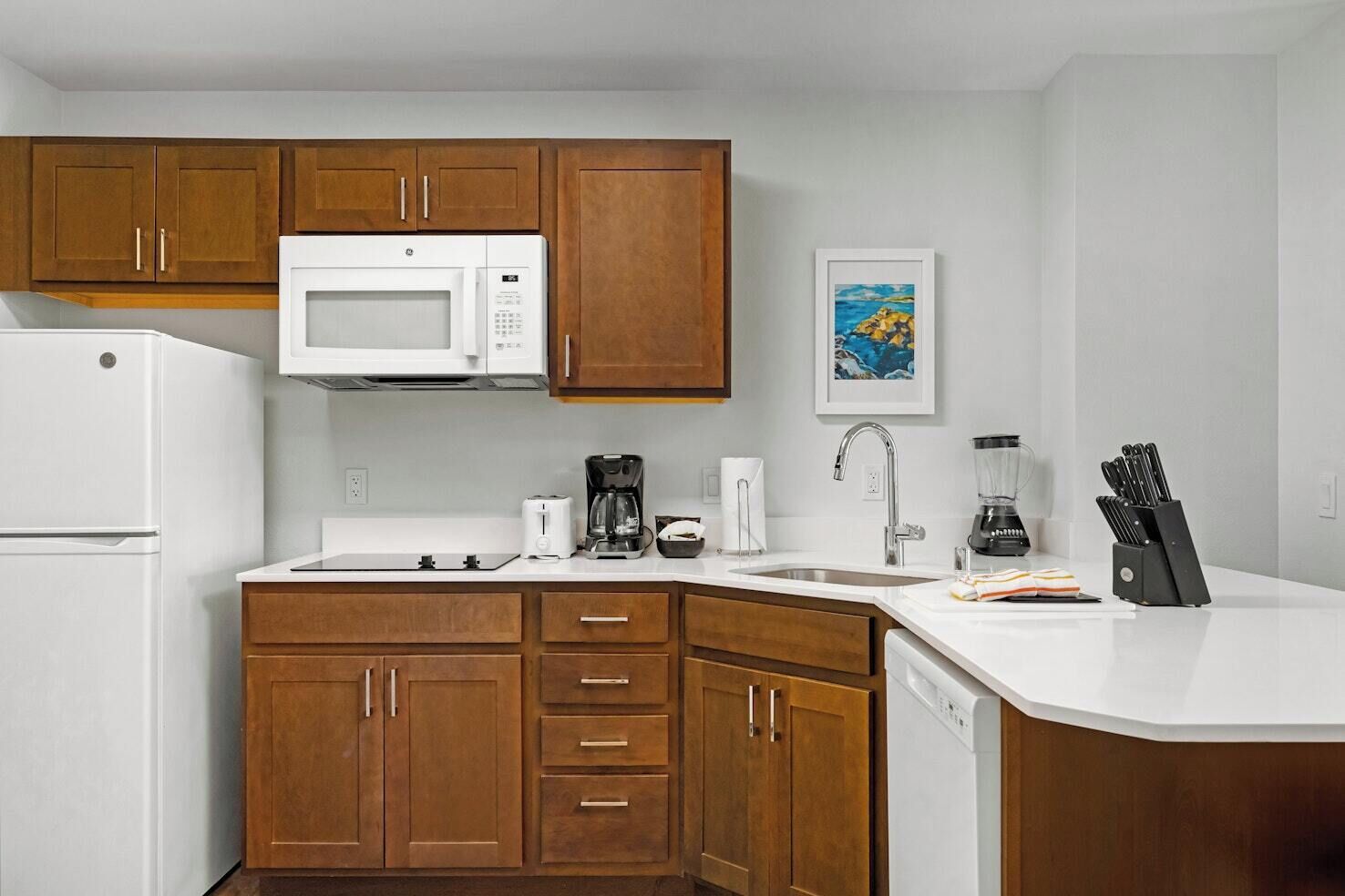 A compact kitchen with a microwave, coffee maker, toaster, sink, and dishwasher.