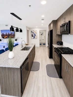 A modern kitchen with a central island, built-in appliances, and a flat-screen TV. - Urban City Luxe | Luxury 2BR | Year-Round Pool | Balcony Views| Walk Everywhere (Atlanta)