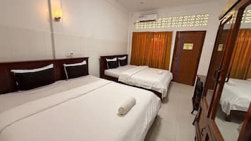 A hotel room with two beds, a wardrobe, a mirror, and a wall-mounted air conditioner.