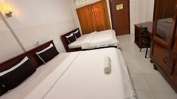 A hotel room with two beds, a wooden wardrobe, a desk, and a curtain.
