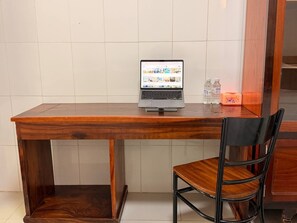 Un escritorio de madera con una computadora portátil, una silla y dos botellas de agua.