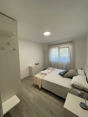 A modern bedroom with a bed, bedside table, and a nightstand.