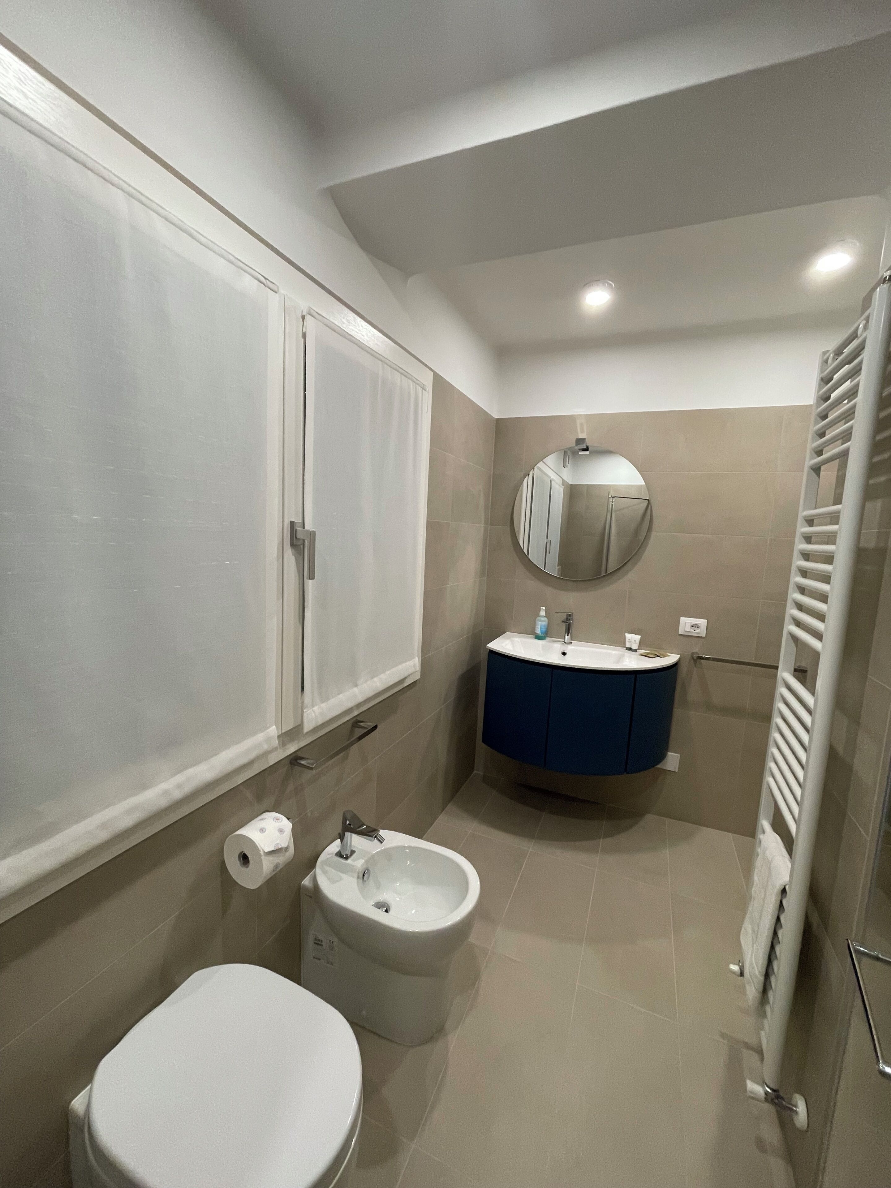 Un baño con inodoro, bidé, tocador con espejo y toallero.