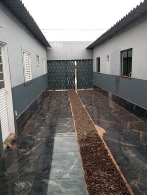 A corridor with a tiled floor, a central gravel path, and a door leading to another area.