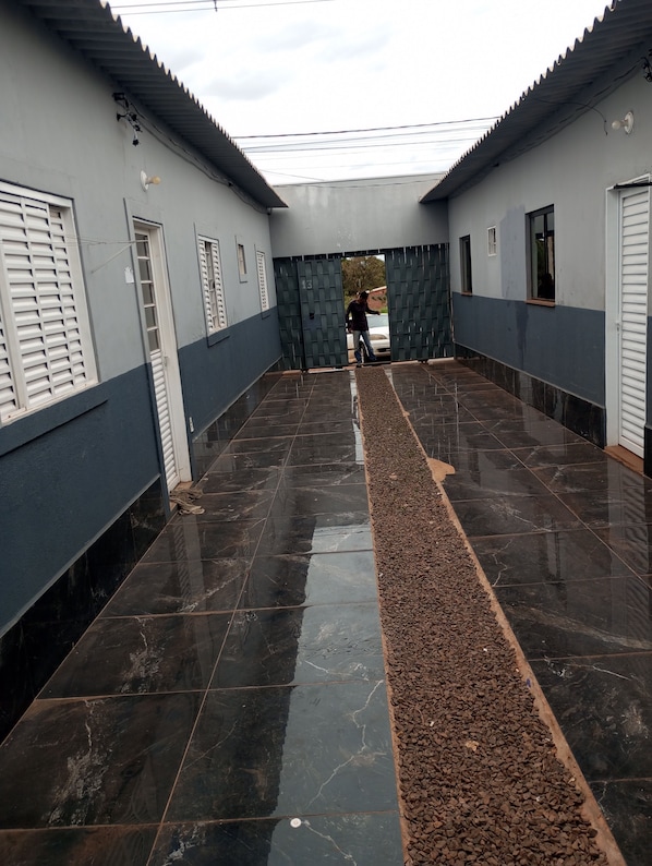 A corridor with a tiled floor, a gravel path, and a gate leading to a vehicle.