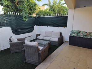 An outdoor patio with wicker furniture, a glass table, and a covered seating area. - CASA RAQUELITA Cozy Townhouse (Los Alcázares)