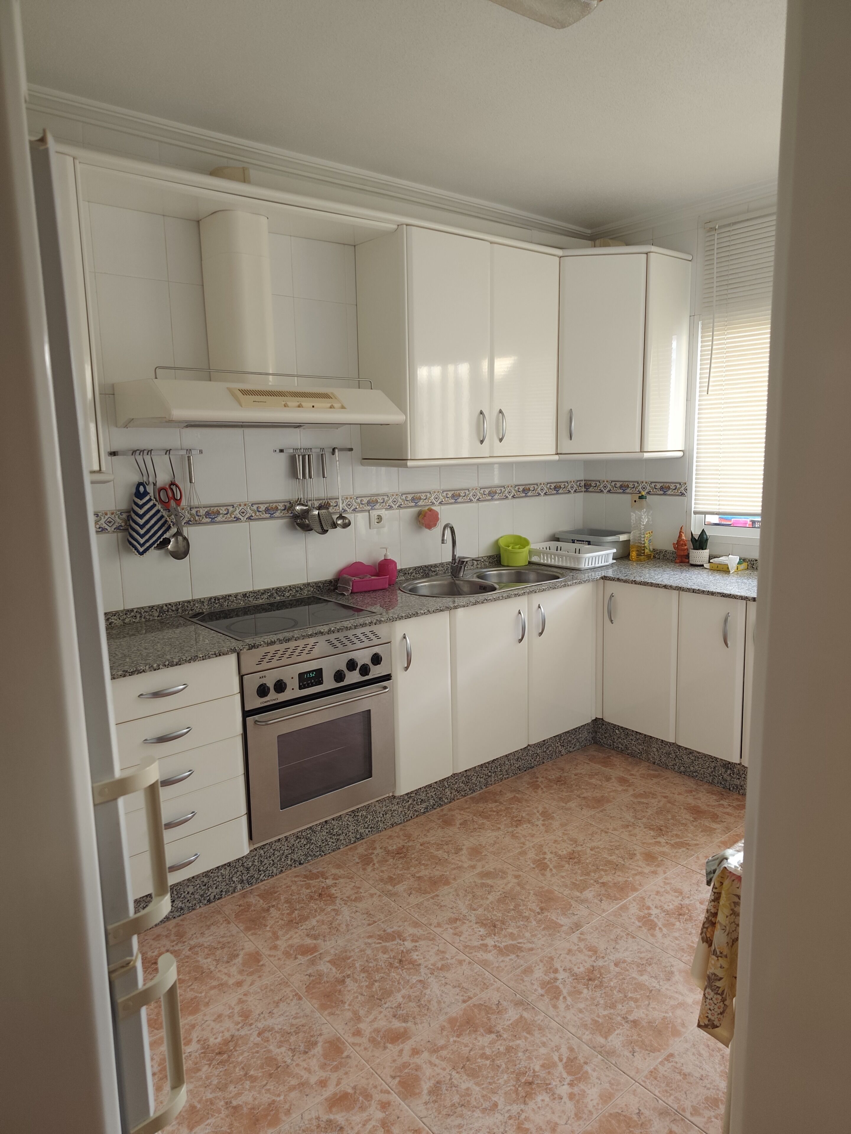 Une cuisine avec des meubles blancs, un four en acier inoxydable et un plan de travail en granit.