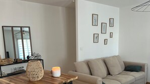 A modern living room with a wooden dining table, a beige sofa, and a patterned rug.