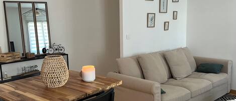 Een moderne woonkamer met een houten eettafel, een beige bank en een kamerbreed tapijt.