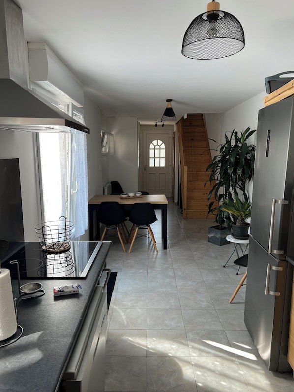 A modern kitchen with a dining area, a refrigerator, and a staircase leading to another level.