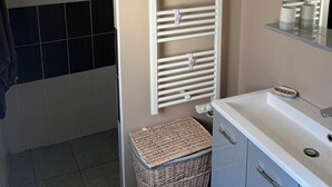A bathroom with a white sink, a mirror, a towel rack, and a trash bin.