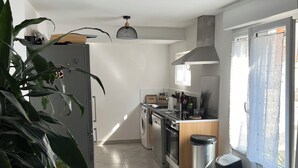 A modern kitchen with a washing machine, a stove, and a trash bin.