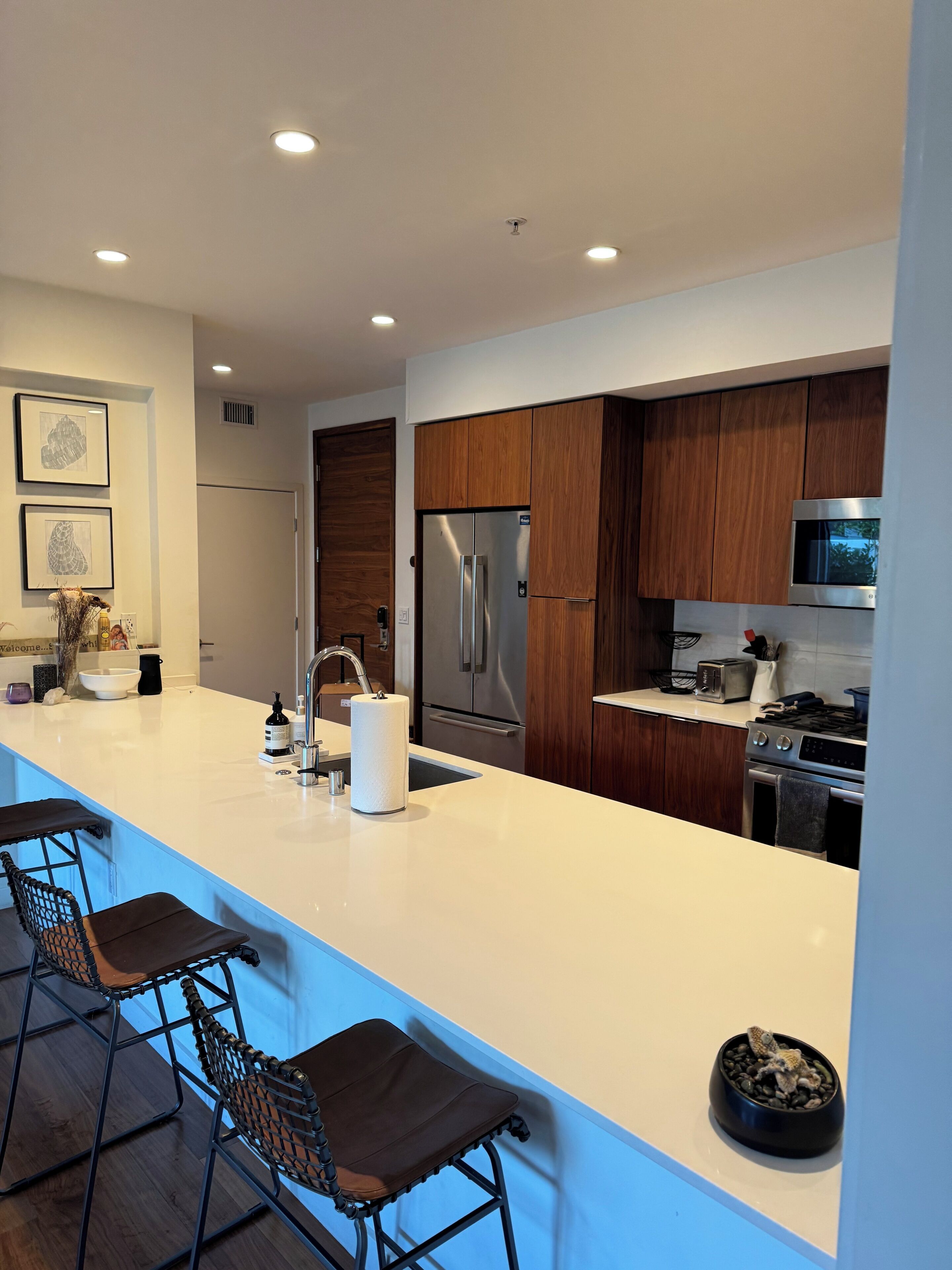 Una cocina moderna con una isla central, electrodomésticos de acero inoxidable y armarios de madera.