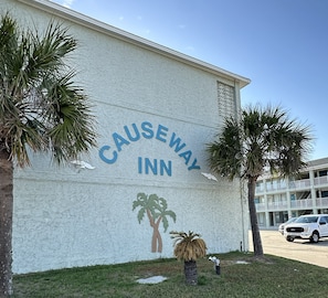 Ein Gebäude mit einem Schild, auf dem 'Causeway Inn' steht, und einer Wandmalerei mit Palmen.