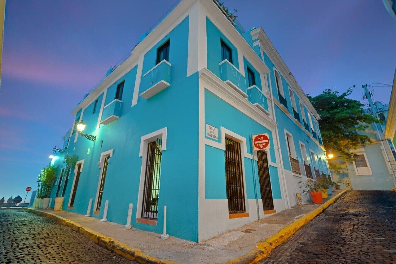 A two-story building with a blue facade, white trim, and barred windows.