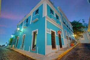 Un edificio a due piani con facciata blu, modanature bianche e finestre sbarrate.