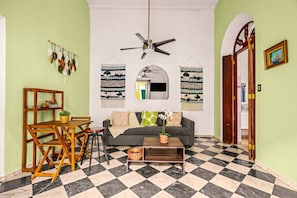 Ein Wohnzimmer mit Schachbrettfußboden, einer Couch, einem Couchtisch und einem Deckenventilator.