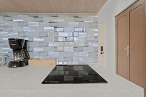 A kitchen with a modern design, featuring a white countertop, a black coffee maker, and a unique tiled backsplash. - T-Mobile District San Juan Next to Beach (San Juan)