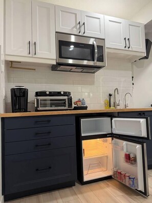 Eine moderne Küche mit weißen Schränken, einer eingebauten Mikrowelle, einem Toasterofen und einem Kühlschrank mit geöffneter Tür.