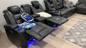 A room with three black massage chairs, each with a footrest and control panel.