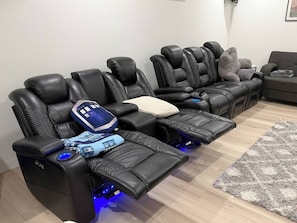 Una habitación con tres sillones de masaje negros, cada uno con reposapiés y panel de control.