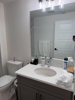 Ein Badezimmer mit einer weißen Toilette, einem Waschbecken mit Spiegel darüber und einem Handtuch an der Wand.