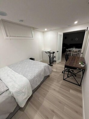 Ein kleines Zimmer mit Bett, Ergometer und Esstisch.
