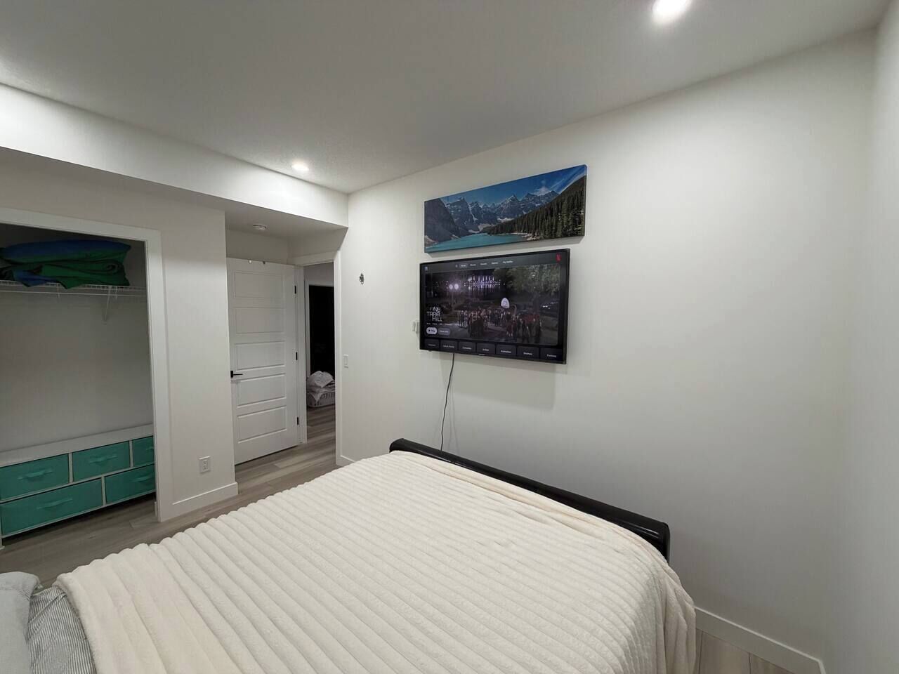 A bedroom with a bed, a TV mounted on the wall, and a wardrobe.