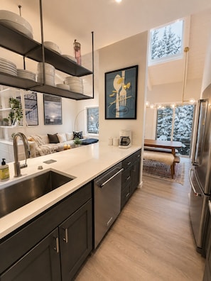 A modern kitchen with a central island, stainless steel appliances, and a view of a snowy landscape. - Cozy 2 bedroom condo in beautiful Snowmass Village with fireplace and hottub (Snowmass Village)