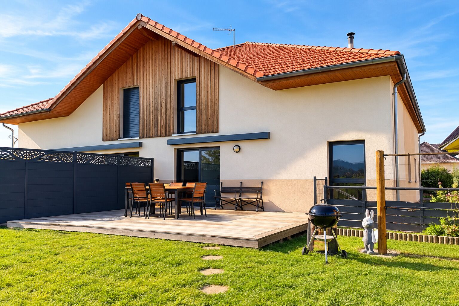 A modern two-story house with a patio, a barbecue grill, and a decorative rabbit statue.