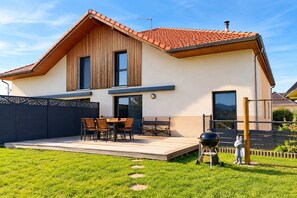 Ein modernes, zweistöckiges Haus mit Terrasse, Grill und einer dekorativen Hasenfigur.