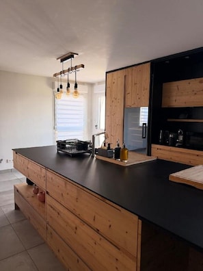 Una cocina moderna con armarios de madera, encimera negra e iluminación colgante.
