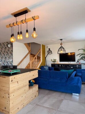 Ein modernes Wohnzimmer mit einem Holztisch, einem blauen Sofa und einem an der Wand befestigten Fernseher.