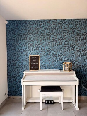 Una habitación con escritorio, un pequeño banco y un papel tapiz estampado.