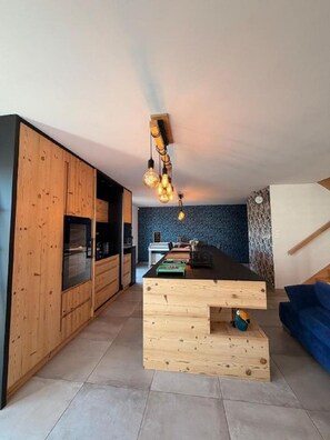 Een moderne keuken met houten kastjes, een centraal eiland en een hangende lamp.