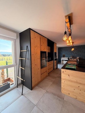 Una cocina moderna con armarios de madera, encimera negra y vistas al exterior.