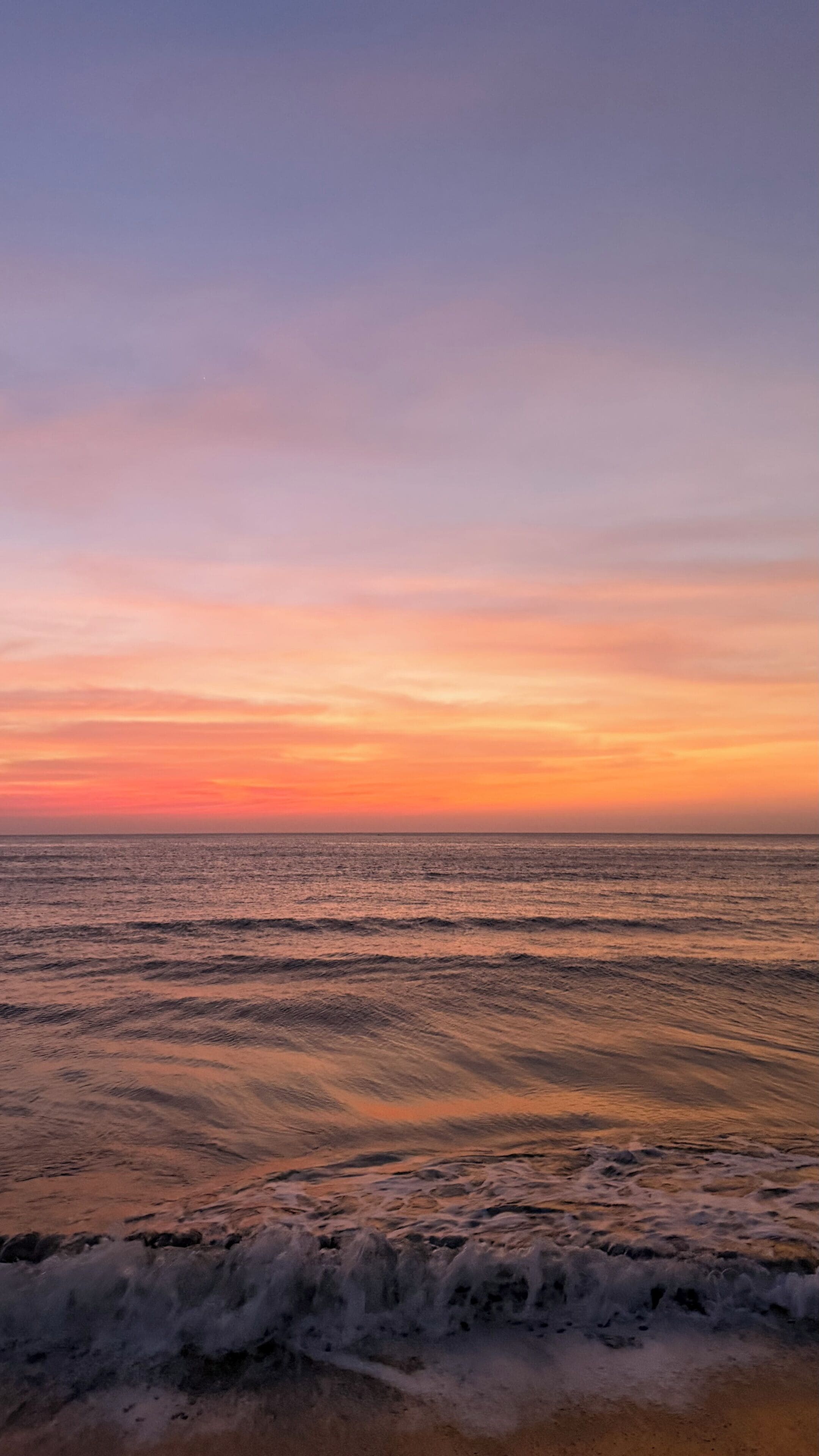 A beach with waves and a sunset.