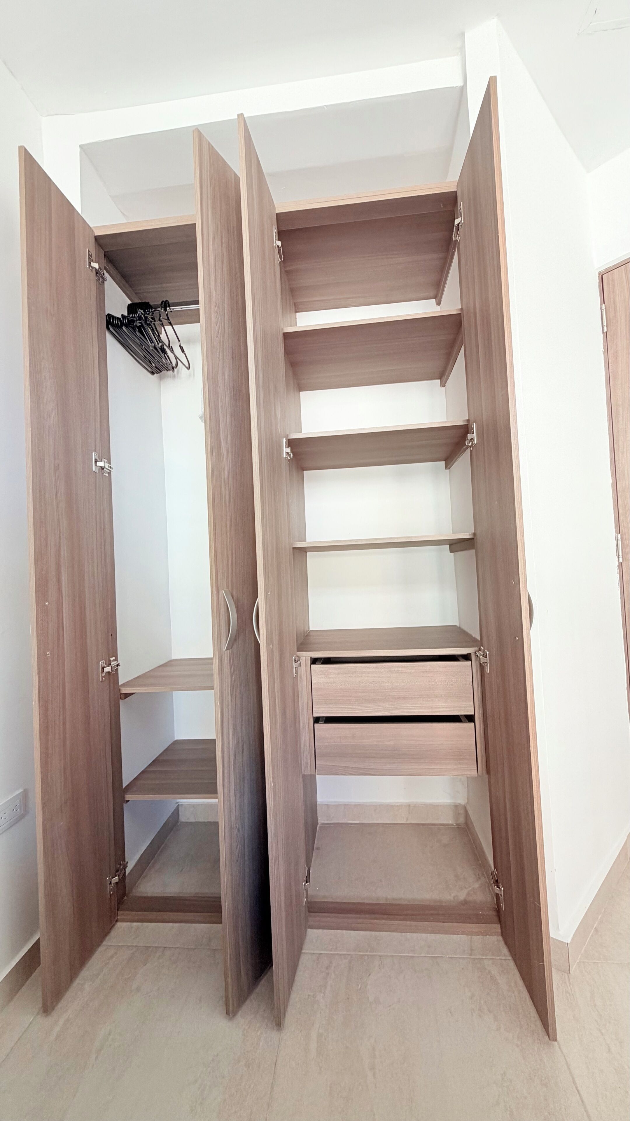 A walk-in closet with open doors, multiple shelves, and a hanging rack.