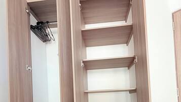A walk-in closet with open doors, multiple shelves, and a hanging rack.