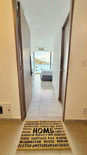 A hallway leading to a bedroom with a view of the outdoors.
