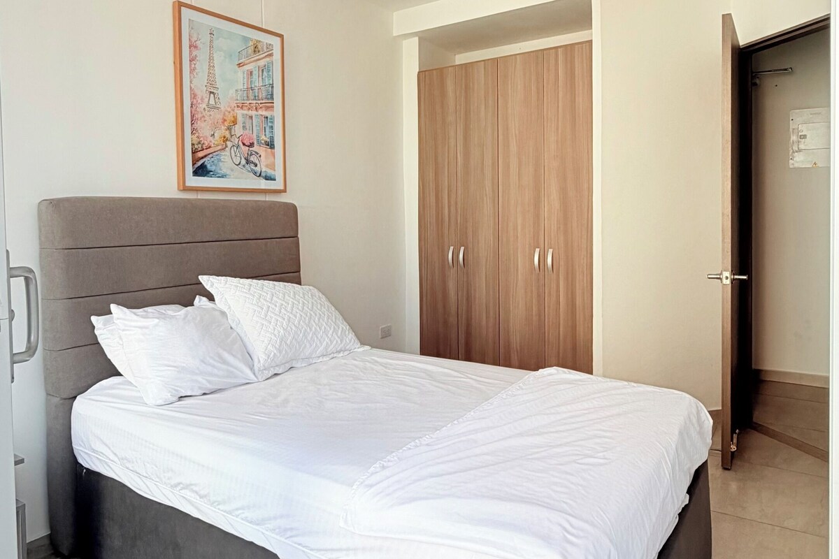 A bedroom with a bed, a wardrobe, and a ceiling vent.