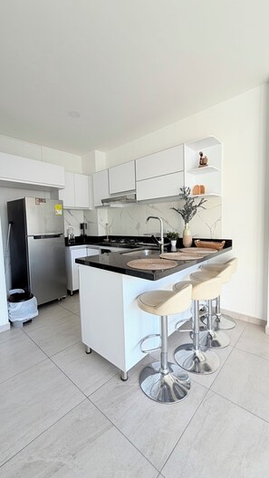 A modern kitchen with a central island, stainless steel appliances, and a bar stool seating area.