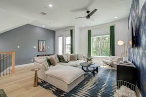 A modern living room with a sofa, coffee table, and a view of greenery outside. - Spa Soaker Tub & Patio Near Downtown Houston & University of Houston (Houston)