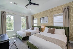 A hotel room with two beds, a desk, a chair, a ceiling fan, and a window with curtains. - Spa Soaker Tub & Patio Near Downtown Houston & University of Houston (Houston)