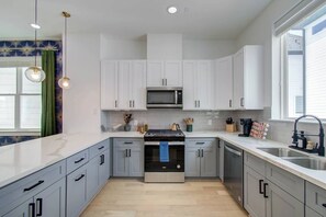 A modern kitchen with white cabinets, a stainless steel sink, and a microwave. - Spa Soaker Tub & Patio Near Downtown Houston & University of Houston (Houston)