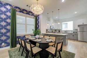 A modern kitchen with white cabinets, a stainless steel refrigerator, and a dining area with a round table and chairs. - Spa Soaker Tub & Patio Near Downtown Houston & University of Houston (Houston)