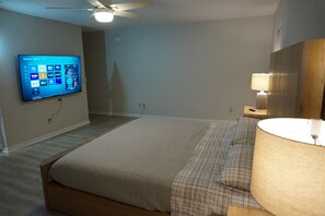 A hotel room with a bed, a TV mounted on the wall, a ceiling fan, and a bedside lamp. - Rainbow springs oasis with solar heated pool. (Dunnellon)