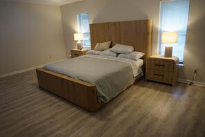 Une chambre à coucher avec un lit en bois, des tables de chevet et une fenêtre avec des stores.