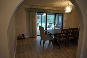 A dining area with a table and chairs, a chandelier, and a view of a pool through large windows. - Rainbow springs oasis with solar heated pool. (Dunnellon)