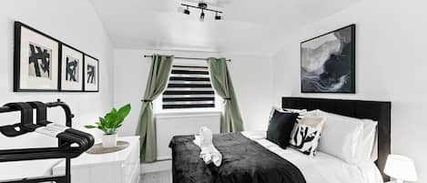 A modern bedroom with a bed, a desk, and a window with curtains.